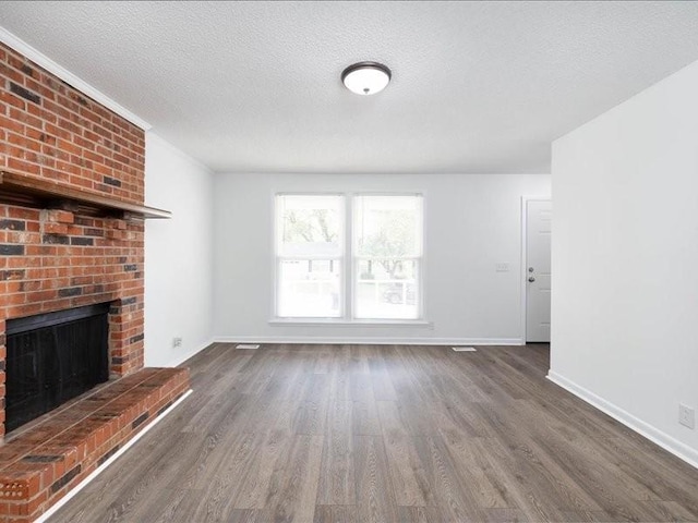 unfurnished living room featuring a textured ceiling, dark hardwood / wood-style flooring, and a brick fireplace