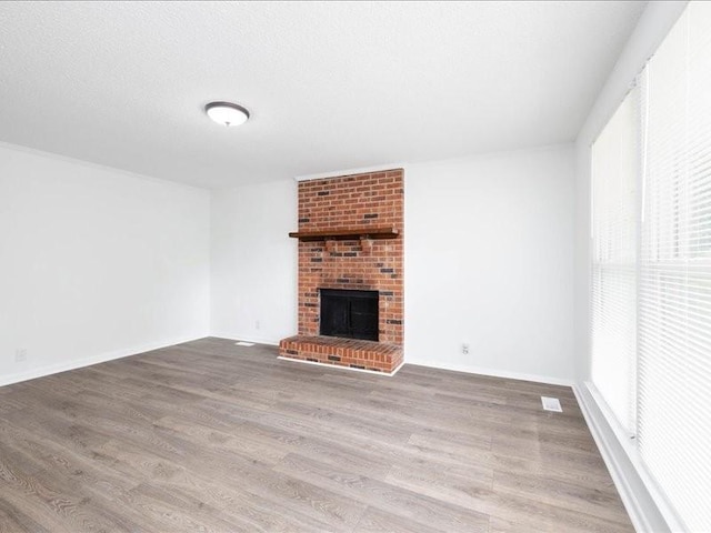 unfurnished living room with a fireplace, a textured ceiling, and hardwood / wood-style flooring