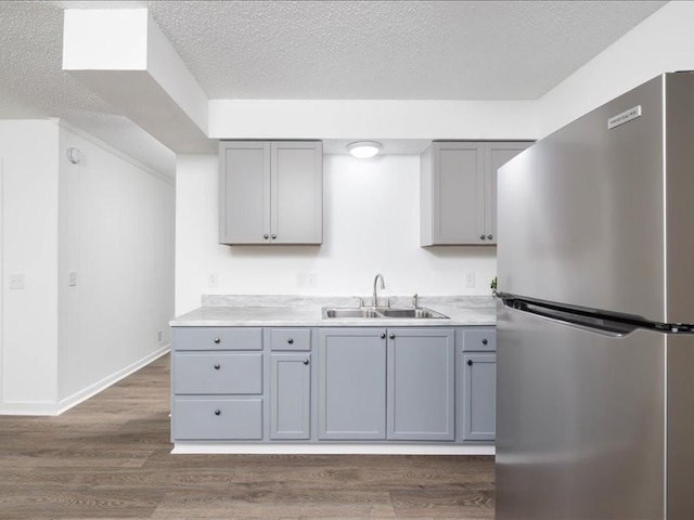 kitchen featuring stainless steel fridge, gray cabinetry, a textured ceiling, dark wood-type flooring, and sink