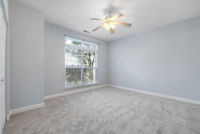 carpeted empty room with ceiling fan and a wealth of natural light