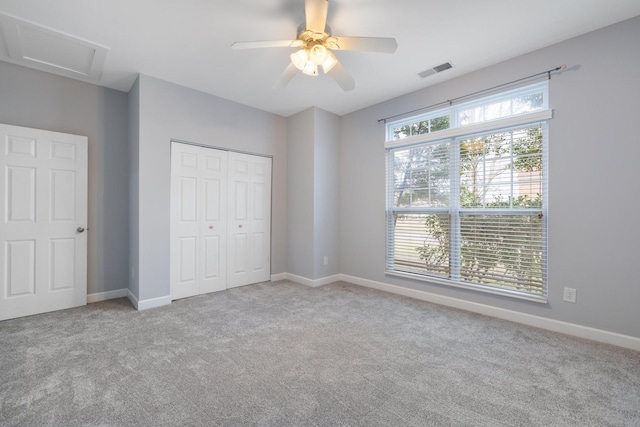 unfurnished bedroom featuring ceiling fan, a closet, light carpet, and multiple windows