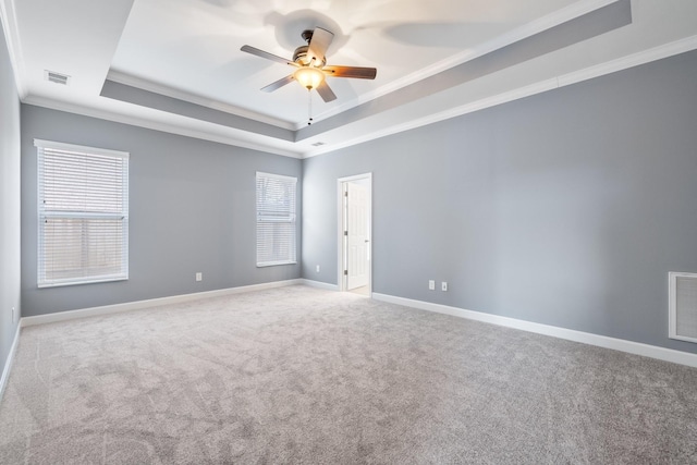 carpeted spare room with ceiling fan, ornamental molding, and a tray ceiling