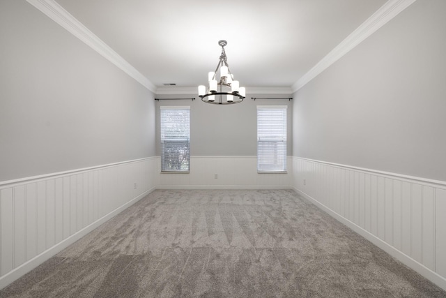 carpeted empty room featuring ornamental molding and a chandelier