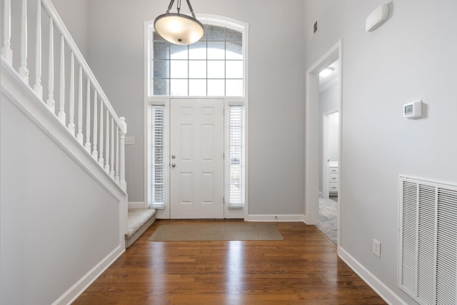 entrance foyer with a towering ceiling and dark hardwood / wood-style floors