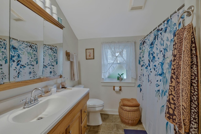 bathroom with tile patterned floors, vanity, vaulted ceiling, and toilet