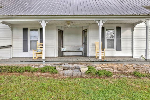 property entrance featuring a lawn, ceiling fan, and a porch