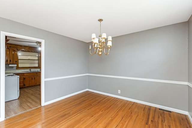 empty room featuring light hardwood / wood-style flooring, a chandelier, and sink