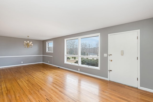 unfurnished room featuring light wood-type flooring and an inviting chandelier