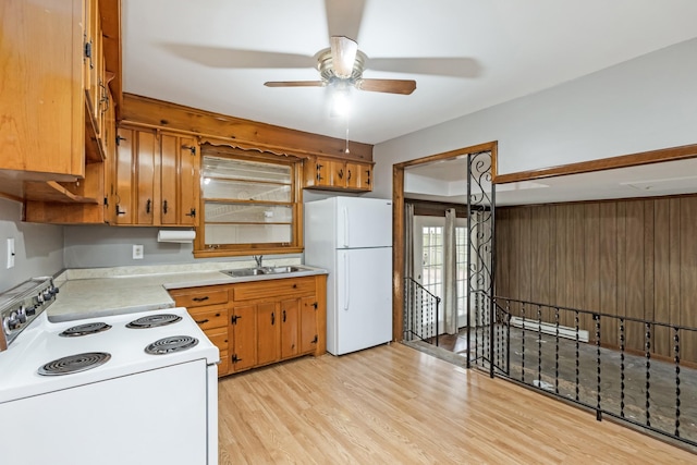 kitchen with white appliances, baseboard heating, ceiling fan, sink, and light hardwood / wood-style floors