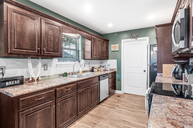 kitchen with sink, light wood-type flooring, tasteful backsplash, dark brown cabinets, and stainless steel appliances