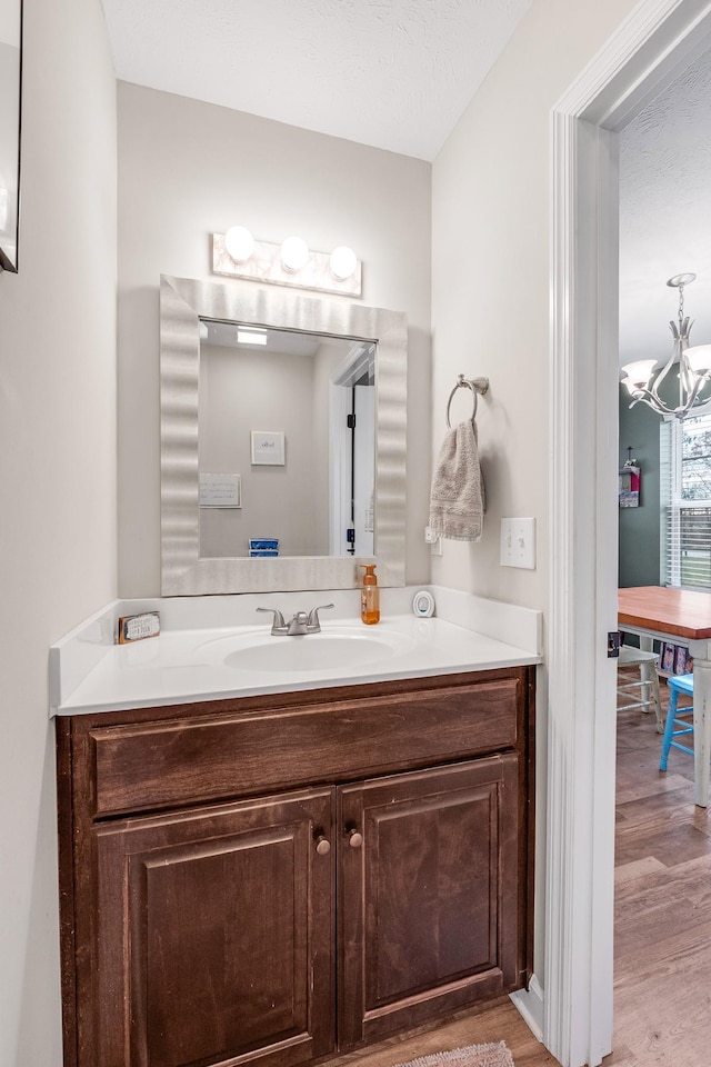 bathroom with vanity, wood-type flooring, a textured ceiling, and a chandelier