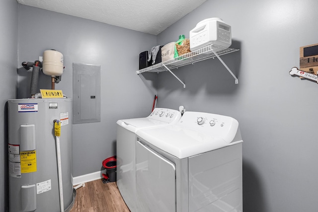 clothes washing area with water heater, independent washer and dryer, electric panel, hardwood / wood-style floors, and a textured ceiling