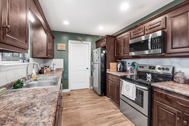 kitchen with dark brown cabinetry, sink, stainless steel appliances, backsplash, and light hardwood / wood-style floors