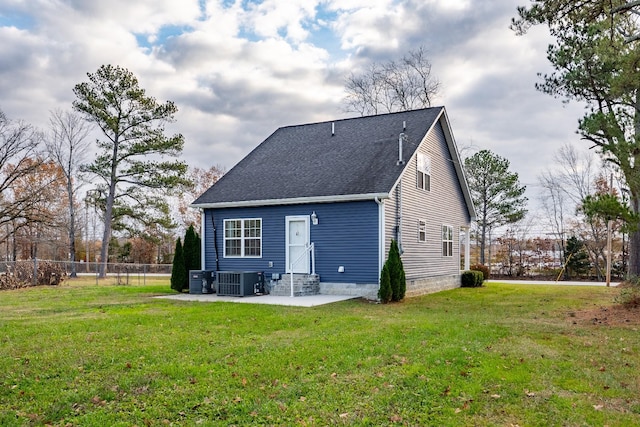 rear view of property with cooling unit, a patio area, and a lawn