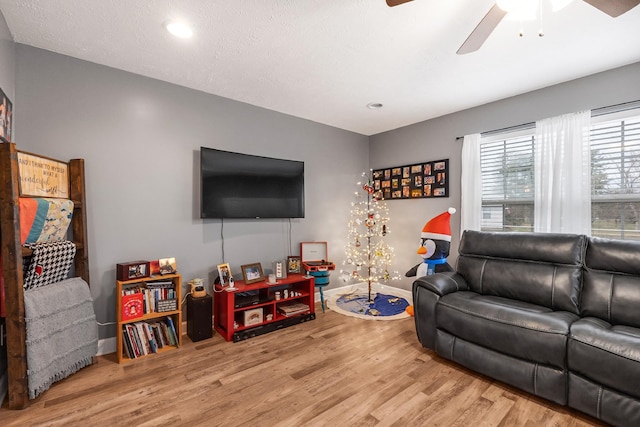 living room featuring ceiling fan, wood-type flooring, and a textured ceiling