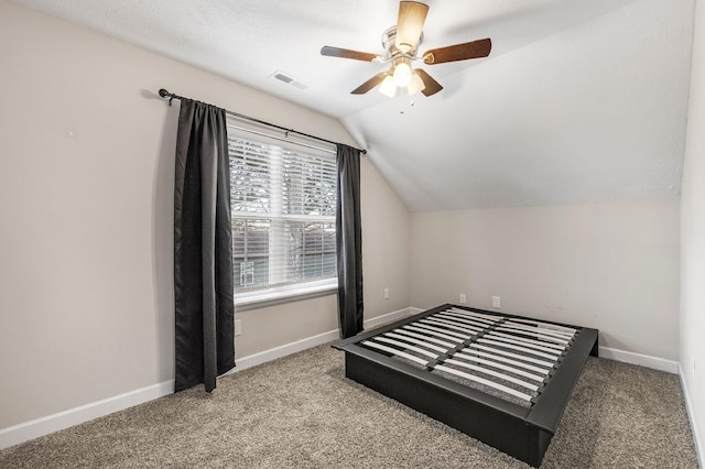 bedroom with carpet flooring, ceiling fan, a textured ceiling, and vaulted ceiling