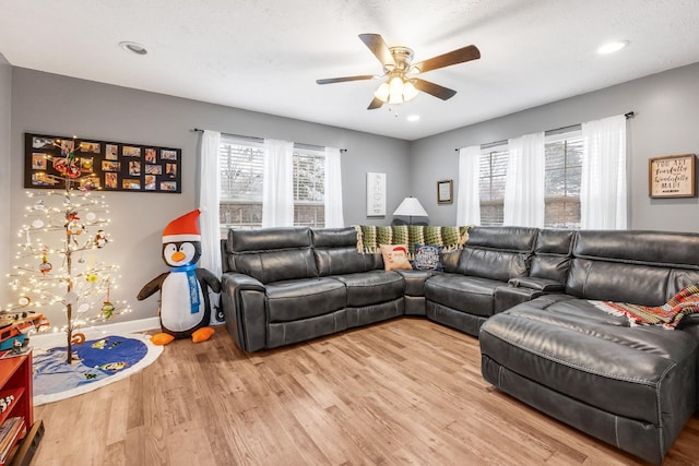 living room with ceiling fan, a textured ceiling, and light hardwood / wood-style flooring