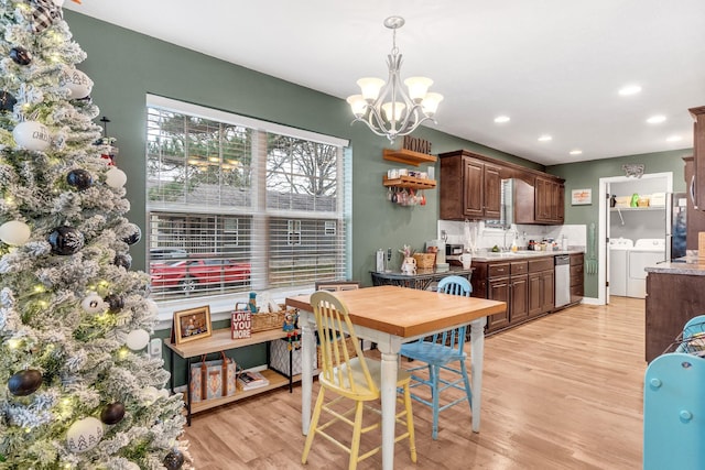 dining area with sink, light hardwood / wood-style flooring, an inviting chandelier, and independent washer and dryer