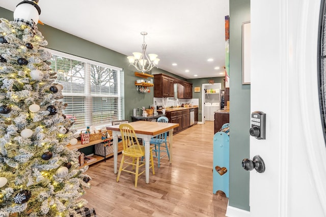 dining space with a chandelier, light hardwood / wood-style flooring, and sink