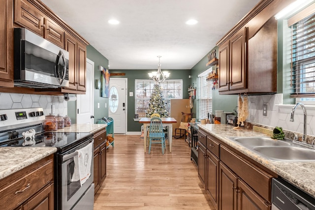 kitchen featuring appliances with stainless steel finishes, light hardwood / wood-style flooring, a healthy amount of sunlight, and sink