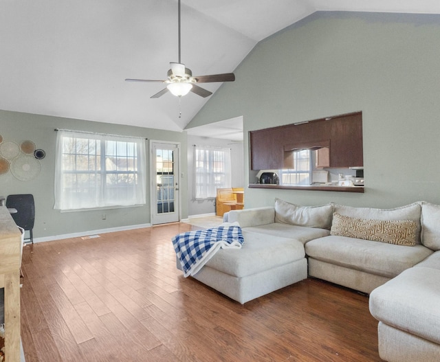 living room with ceiling fan, plenty of natural light, high vaulted ceiling, and wood-type flooring