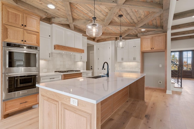 kitchen with wooden ceiling, a center island with sink, sink, beamed ceiling, and decorative light fixtures