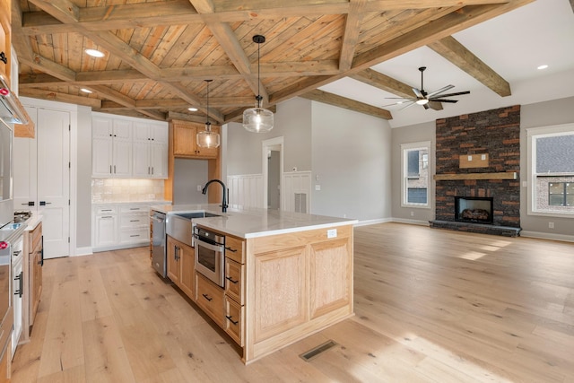 kitchen with a wealth of natural light, sink, an island with sink, and hanging light fixtures