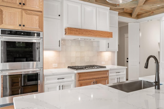 kitchen featuring white cabinets, stainless steel appliances, light stone counters, and sink