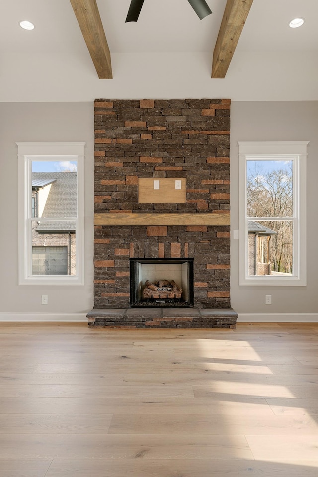 unfurnished living room featuring beam ceiling, light hardwood / wood-style floors, and a fireplace