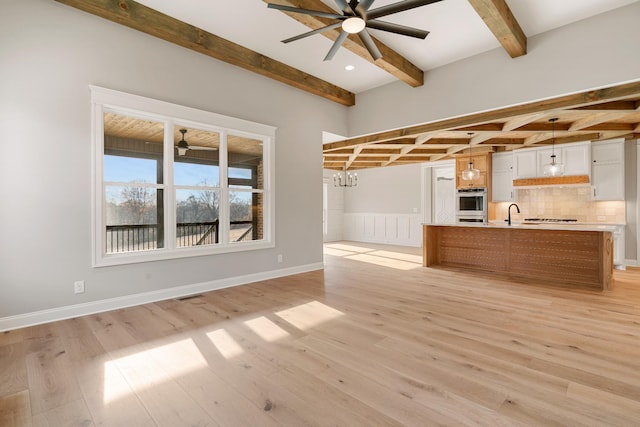 kitchen with white cabinetry, stainless steel double oven, hanging light fixtures, tasteful backsplash, and light hardwood / wood-style flooring