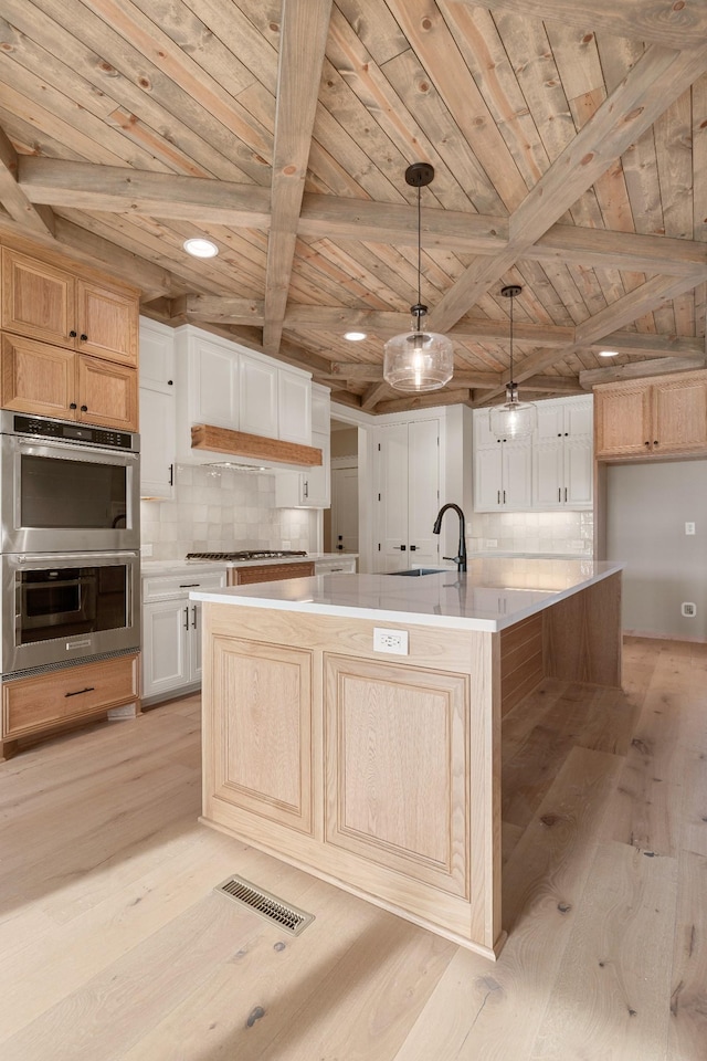 kitchen with hanging light fixtures, light hardwood / wood-style flooring, a spacious island, white cabinets, and wood ceiling