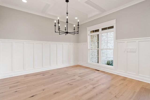 unfurnished dining area with a chandelier, light wood-type flooring, and crown molding