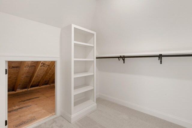 spacious closet with light colored carpet and vaulted ceiling