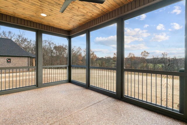 unfurnished sunroom featuring wood ceiling, ceiling fan, and a healthy amount of sunlight