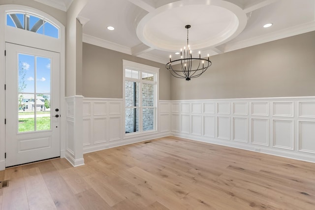 foyer featuring light wood-type flooring, ornamental molding, and an inviting chandelier