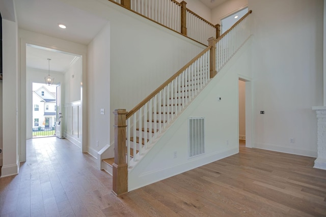 staircase featuring a towering ceiling and hardwood / wood-style flooring