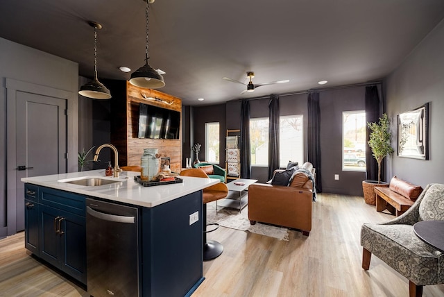 kitchen featuring blue cabinetry, ceiling fan, hanging light fixtures, light hardwood / wood-style flooring, and a kitchen island with sink