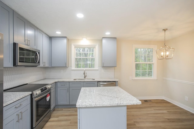 kitchen featuring a kitchen island, light hardwood / wood-style floors, stainless steel appliances, and a wealth of natural light