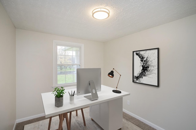 carpeted home office with a textured ceiling