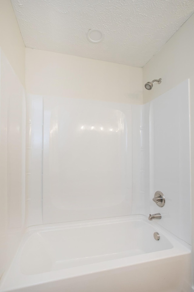 bathroom featuring a textured ceiling and  shower combination