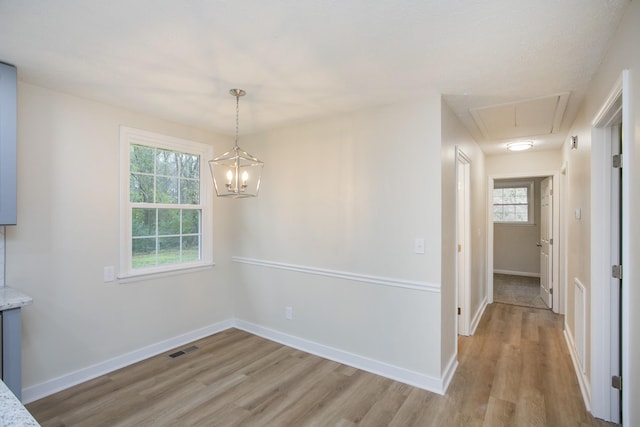 unfurnished dining area featuring a notable chandelier and light wood-type flooring