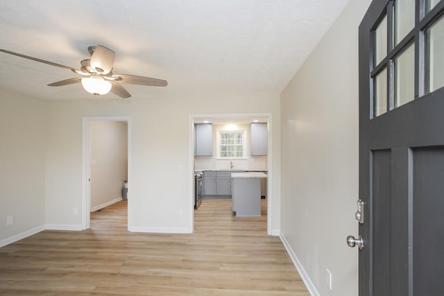 interior space with a textured ceiling, light hardwood / wood-style flooring, ceiling fan, and sink