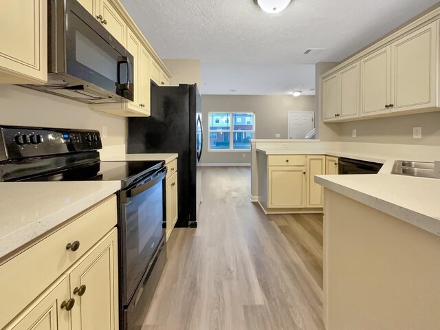 2002 Arum Ct, Spring Hill, TN 37174 - kitchen with black appliances, cream cabinets, light wood-style floors, a peninsula, and a textured ceiling