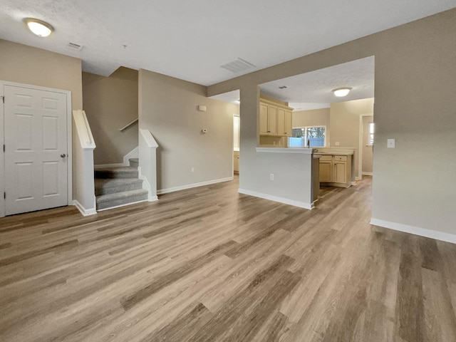 unfurnished living room with a textured ceiling and light wood-type flooring