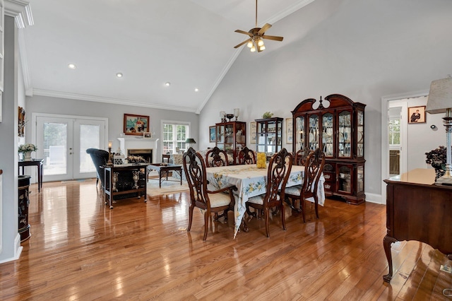 dining space with french doors, light wood-type flooring, ornamental molding, ceiling fan, and high vaulted ceiling