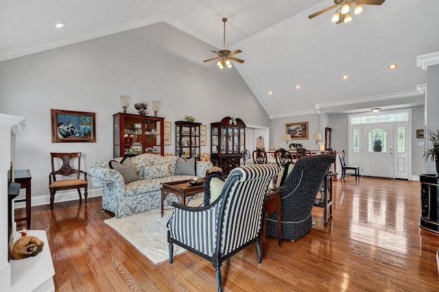 living room featuring ceiling fan, light hardwood / wood-style flooring, high vaulted ceiling, and ornamental molding