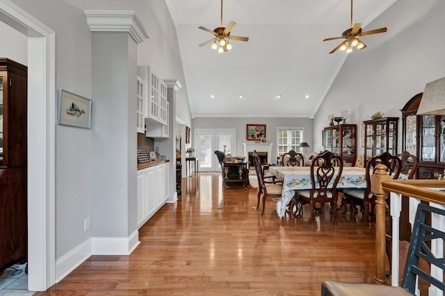 dining space featuring light hardwood / wood-style floors, high vaulted ceiling, ceiling fan, and crown molding