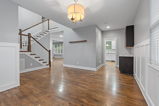 unfurnished living room with a chandelier, plenty of natural light, and dark wood-type flooring