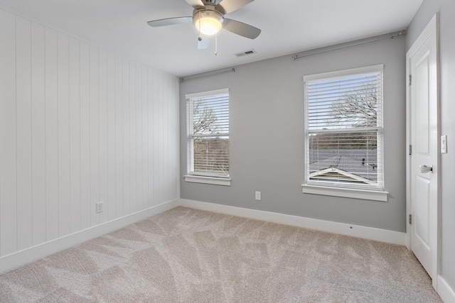 carpeted spare room featuring ceiling fan and plenty of natural light