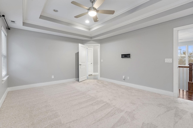 carpeted empty room featuring a raised ceiling, ceiling fan, and ornamental molding